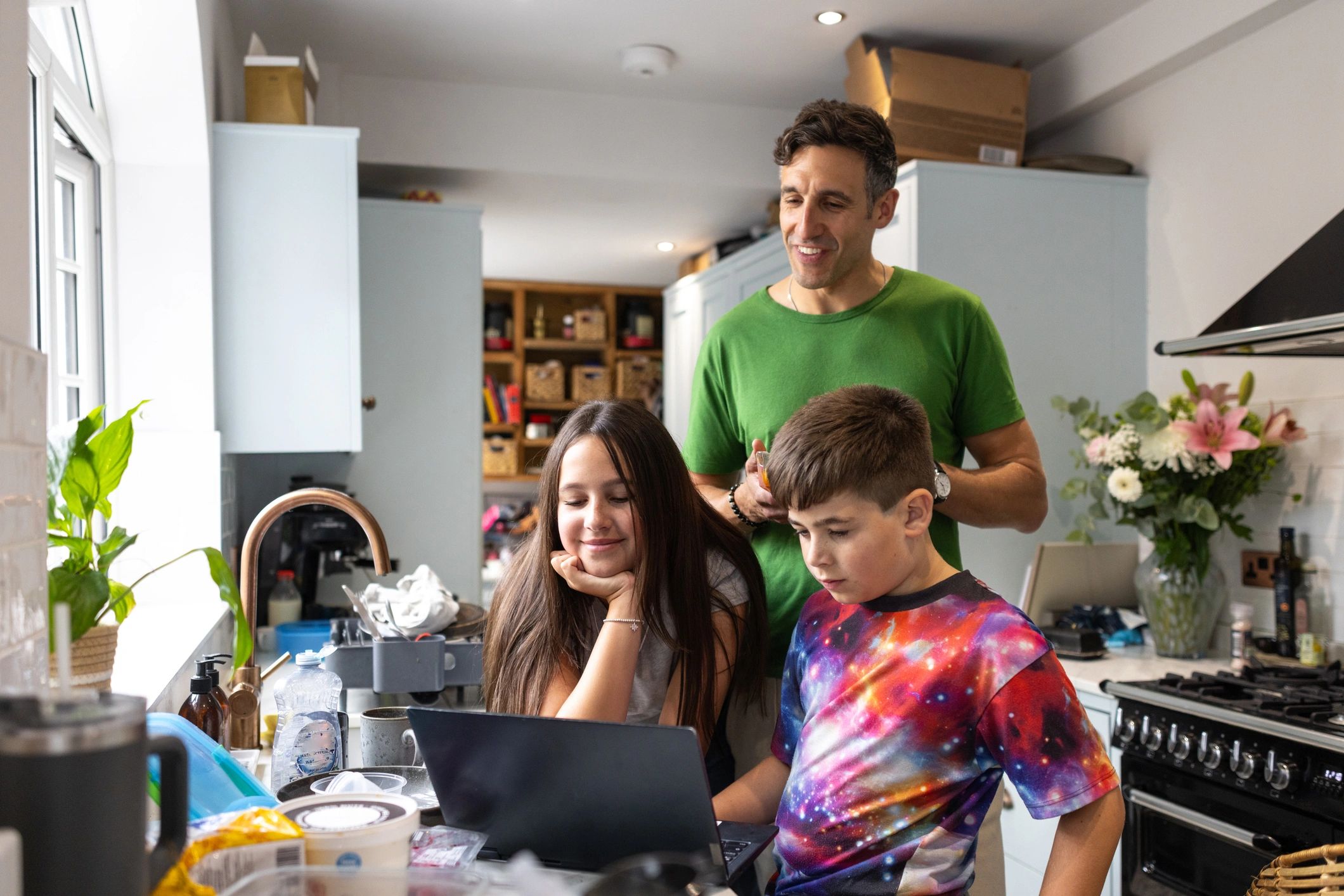 Family gathered around a laptop in a home kitchen
