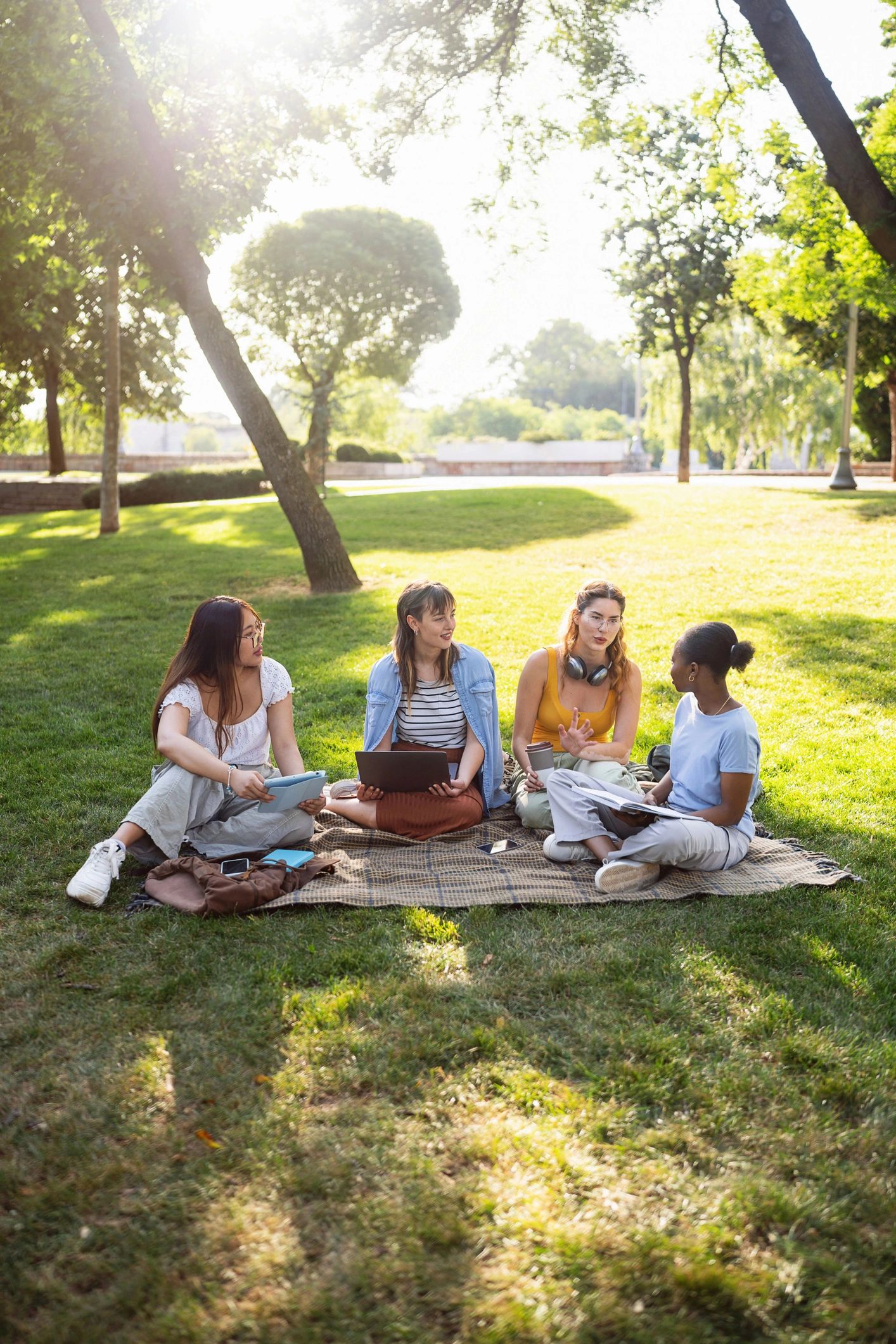 College students studying together outdoors with a laptop and tablet