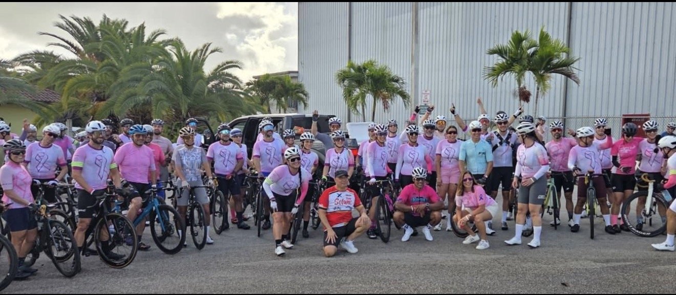 Large group of cyclists in pink jerseys gathered before the Ride Against Cancer